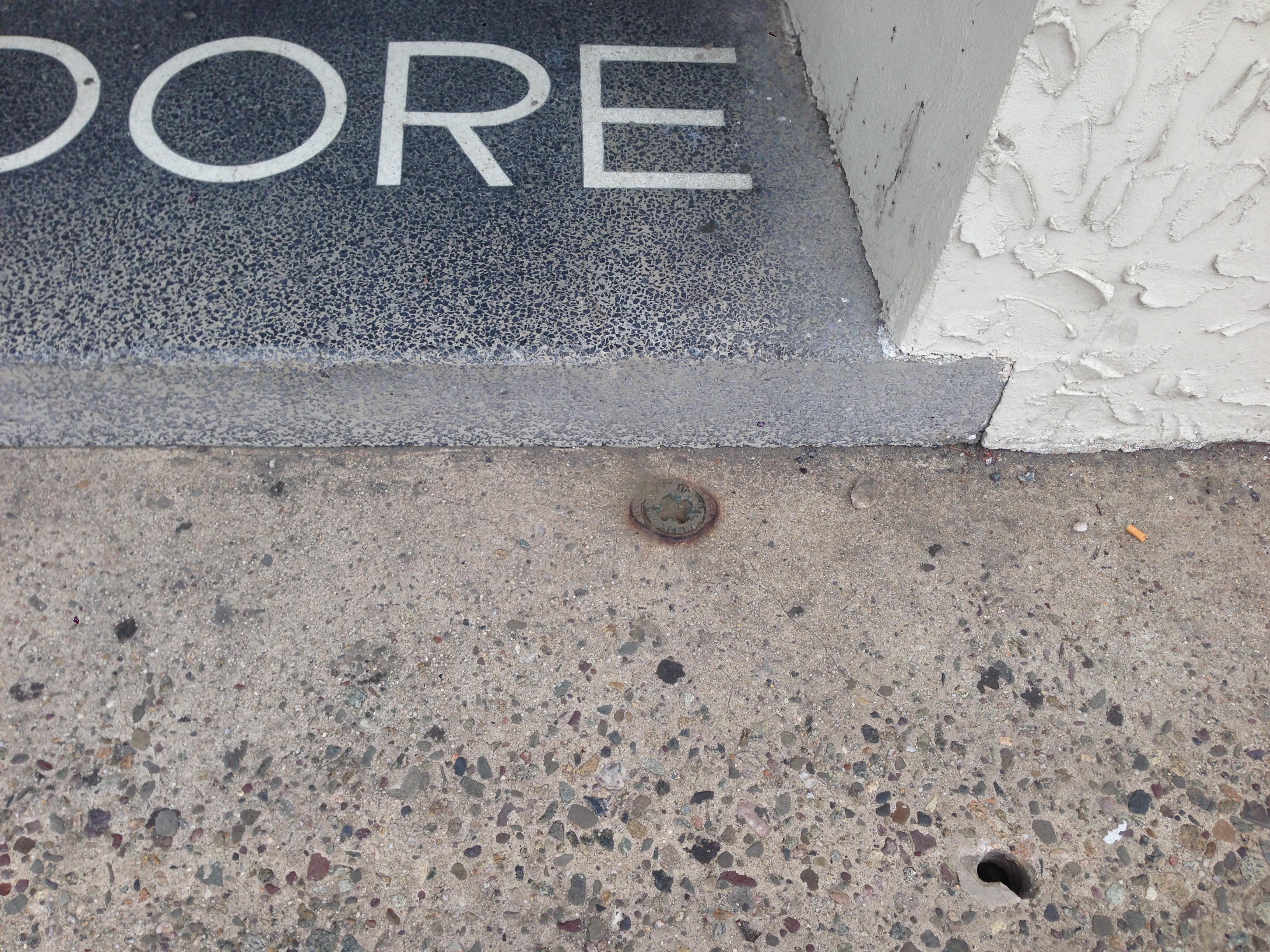 Oil tank fill cap in a concrete sidewalk